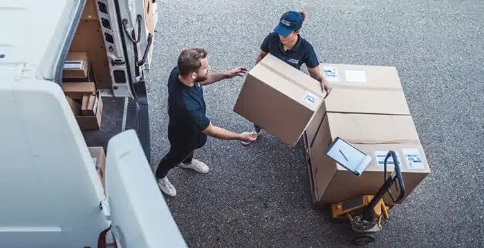 Two people taking boxes out of a van.